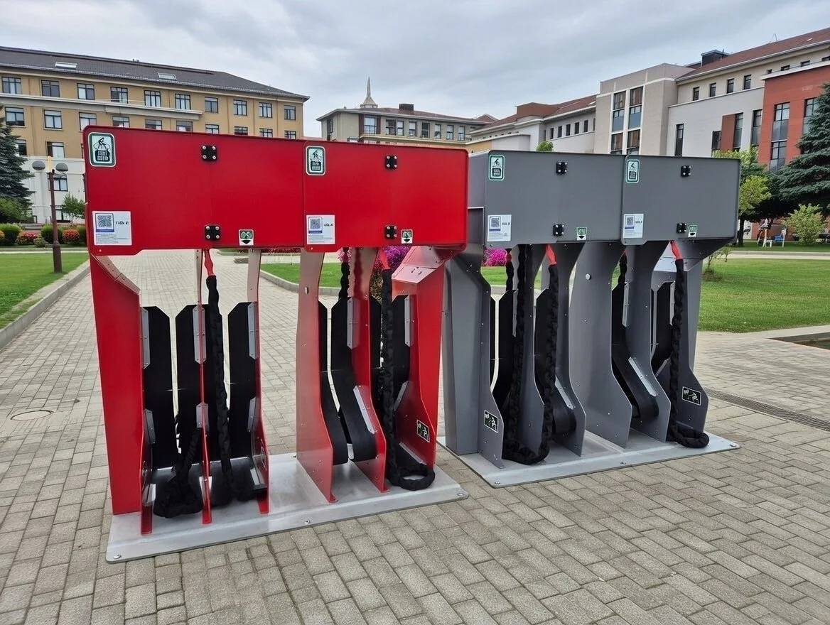 Bike-sharing stations with red and gray lockers in a park area