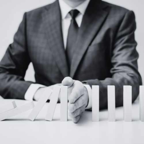 A person in a suit stopping a row of falling dominoes