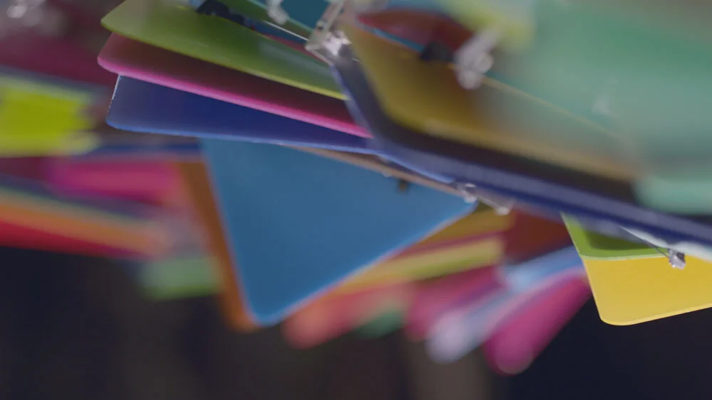 Close-up of colorful paper or cardboard sheets stapled together, viewed from below.