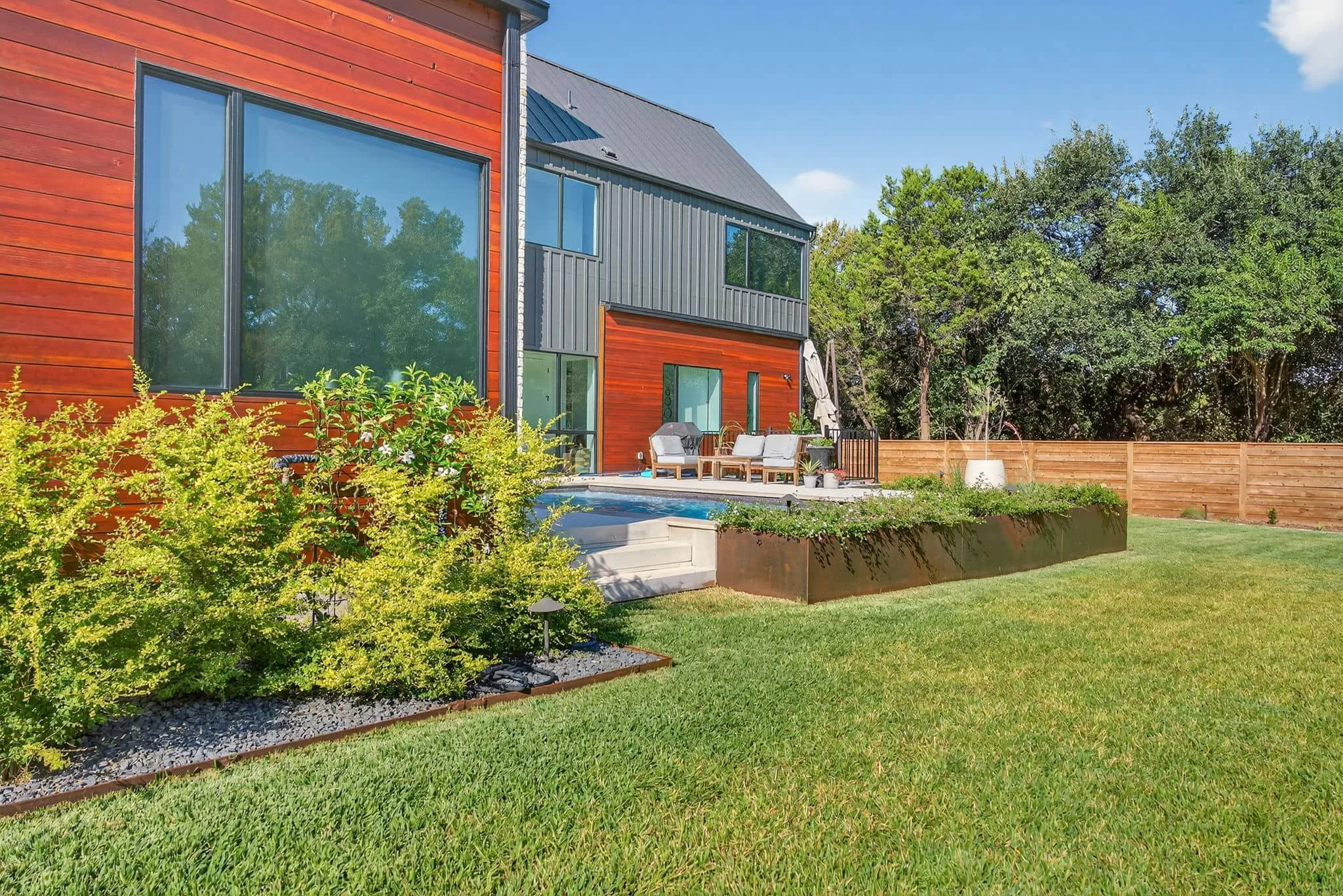 Contemporary outdoor living area with layered landscaping and raised planter beds — Southern Love