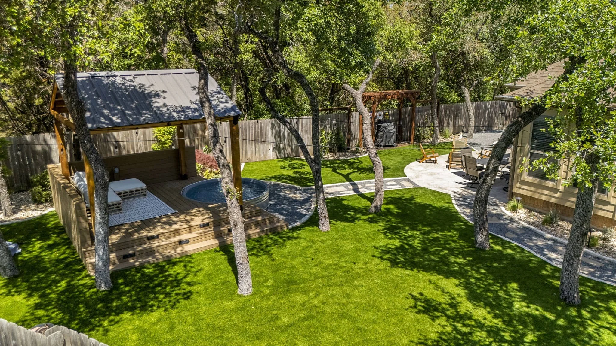 Outdoor entertainment space with custom walkways and covered backyard lounge — Southern Love