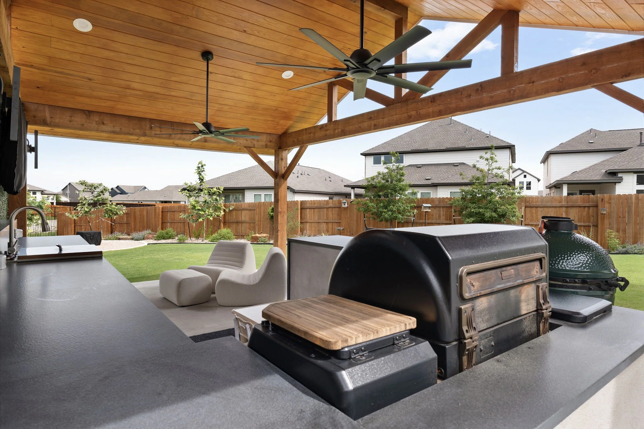 Outdoor kitchen with concrete countertops, built-in grill, kamado smoker, and stained tongue-and-groove ceiling