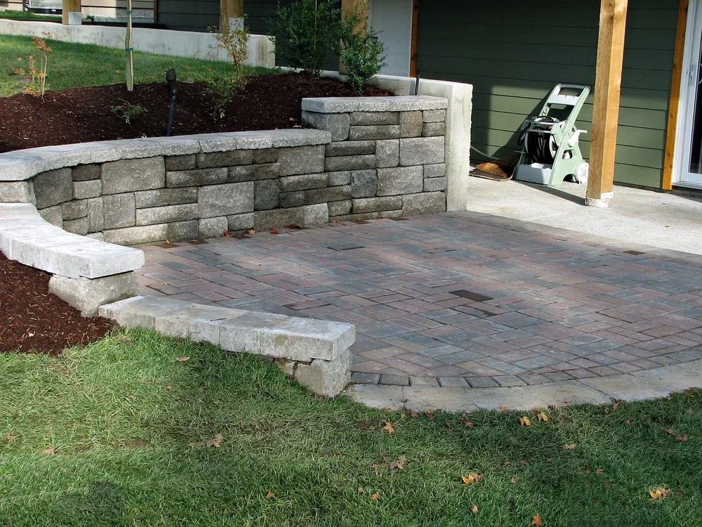 Curved retaining wall with patio pavers offers stability and drainage control during heavy February rain.