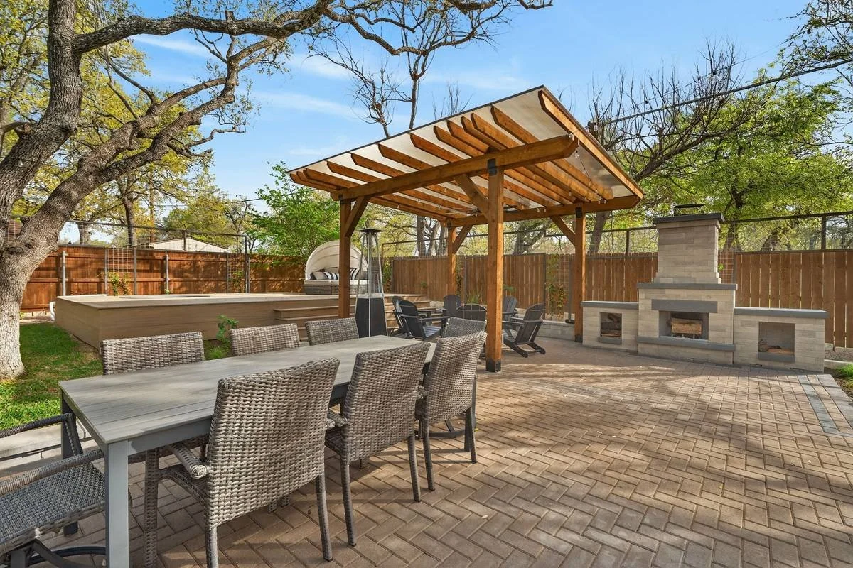 Outdoor dining table near the cedar pergola, stone fireplace and raised deck — Southern Love Landscaping & Design