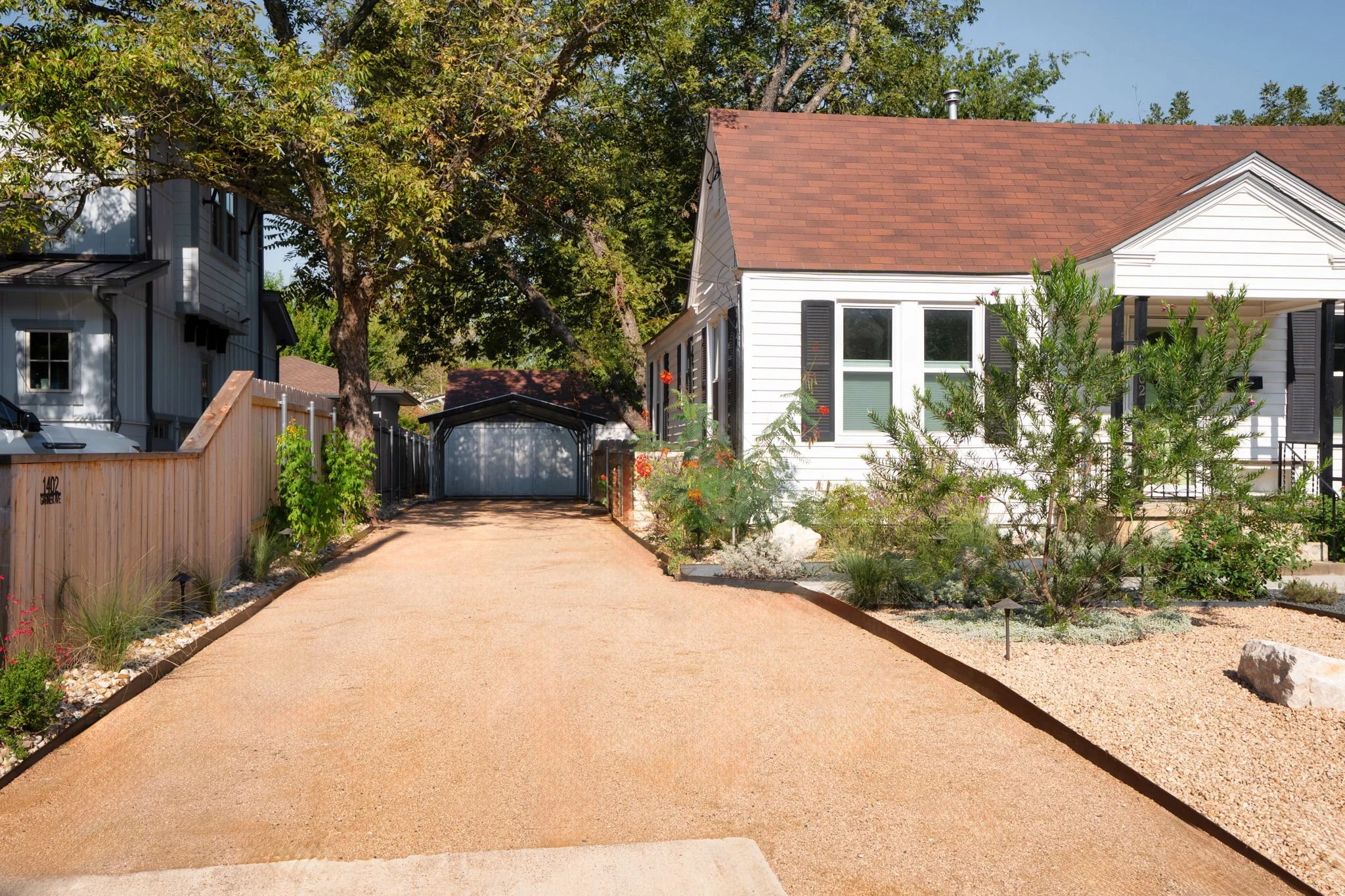 Decomposed granite walkway leading to detached garage, edged with native plantings and accent boulders