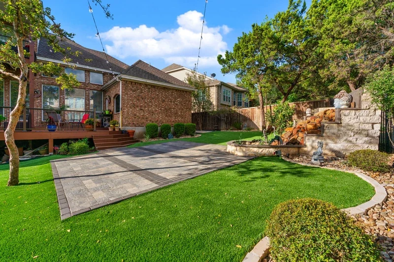 Detailed hardscaping design with paver patio, rock waterfall, and artificial turf, showing January-ready backyard renovation.