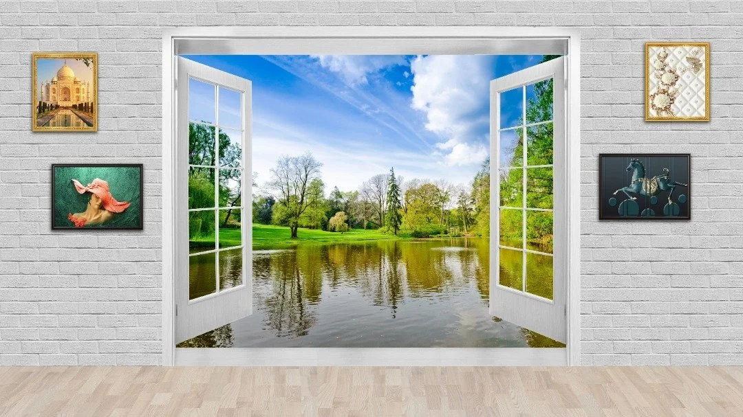 Wall mural of an open window overlooking a serene lake and lush greenery, with framed artwork hanging on a white brick wall.