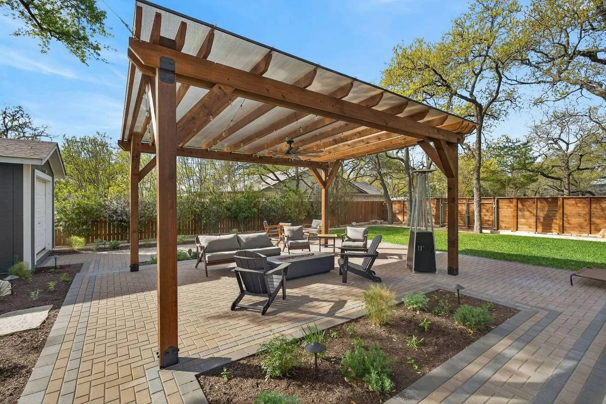 Cedar pergola with a polycarbonate roof over lounge seating and planting beds — Southern Love Landscaping & Design