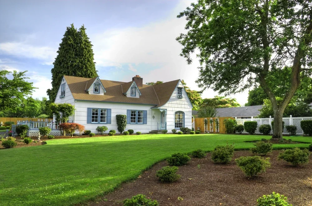 Classic home with lush green lawn, neatly trimmed shrubs, and winter-prepped landscaping ready for seasonal lawn maintenance.