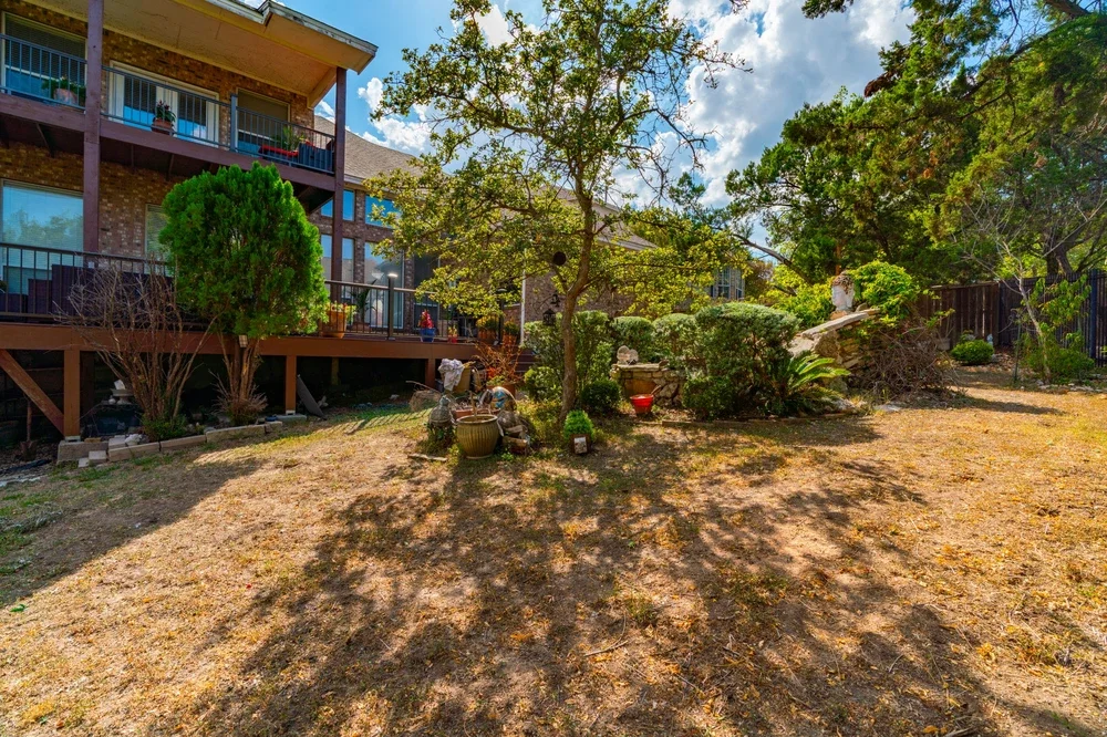 Overgrown and patchy backyard with cluttered pots and dry grass, ideal for a pre-spring yard clean-up in Austin TX.