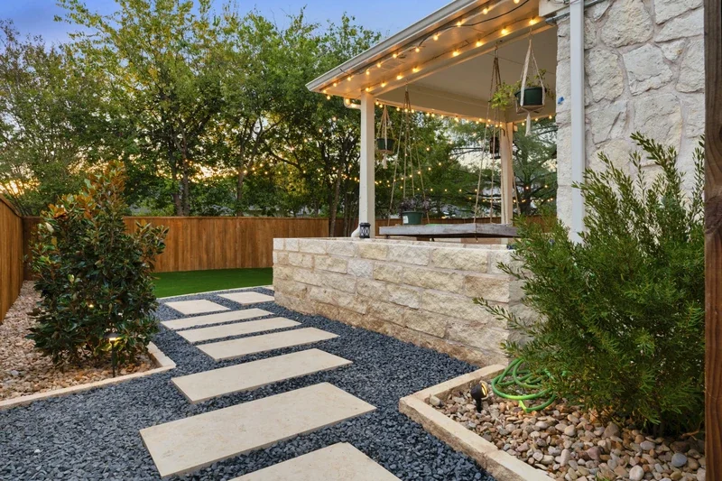 Modern stone patio with string lights and a small pergola entryway, part of a safe and stylish Austin pergola installation.