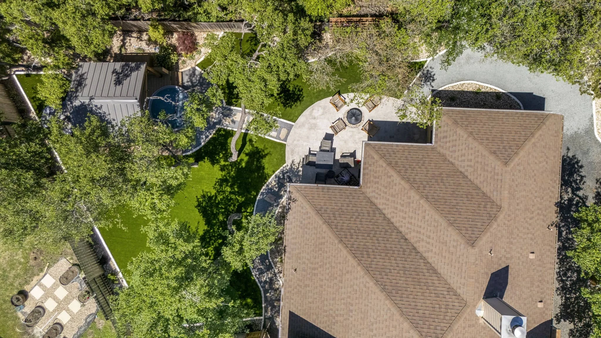 Modern backyard retreat with artificial grass, mature shade trees, and outdoor seating area — Southern Love
