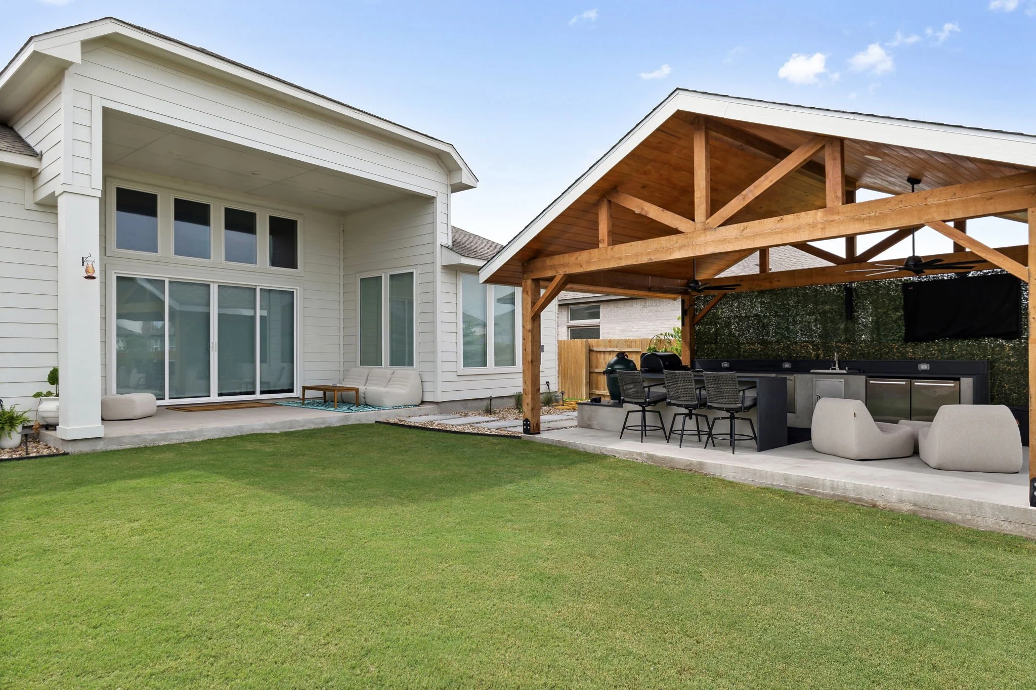 Rear elevation with attached cedar pavilion, extended concrete patio, and sliding glass doors to the lawn
