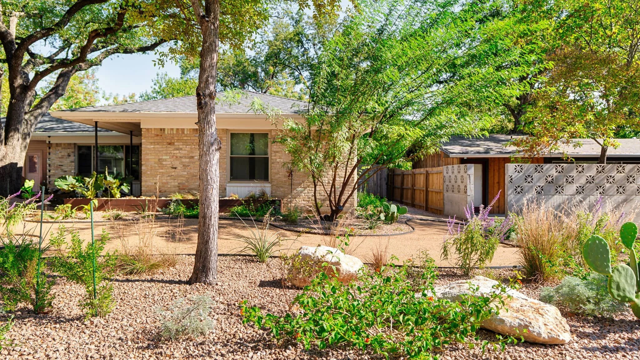 Custom low-maintenance landscaping designed around mature trees and brick architecture — Southern Love