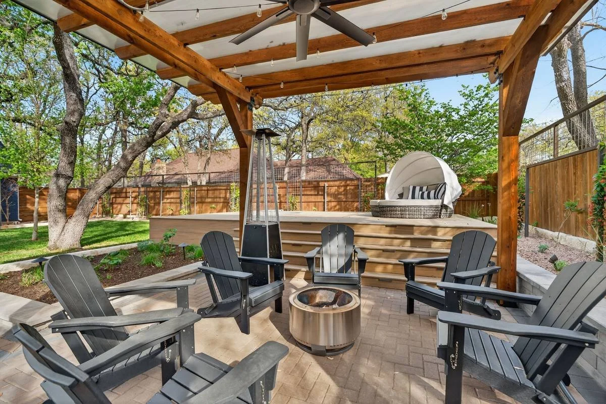 Fire pit circled by Adirondack chairs under a pergola beside the raised deck — Southern Love Landscaping & Design