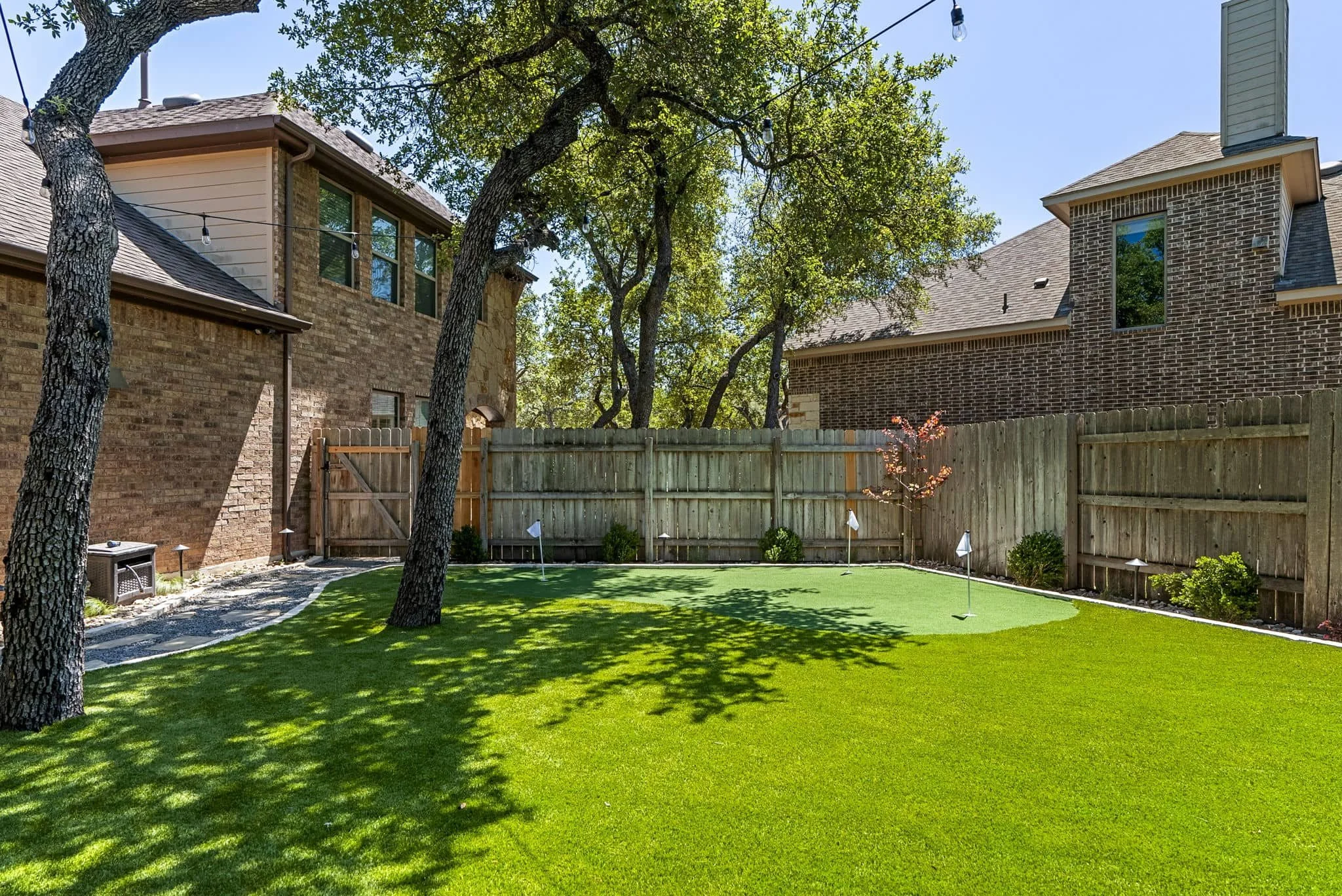 Artificial turf backyard with modern landscape design and shaded seating area — Southern Love