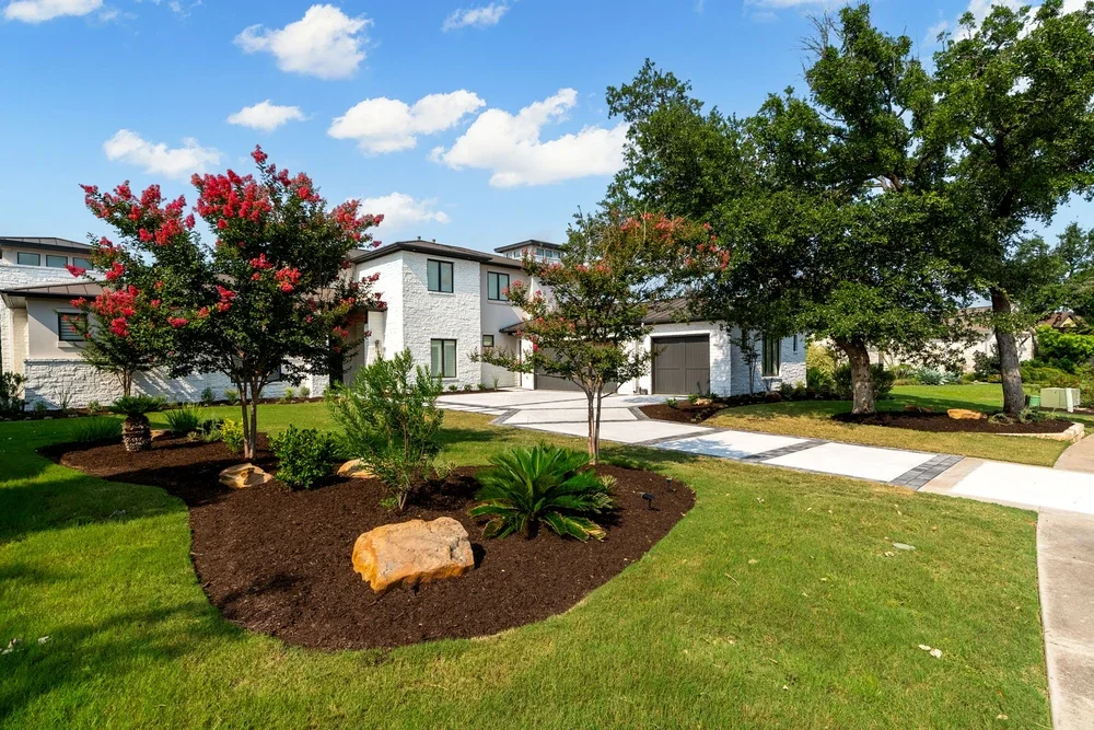 Landscaping with fresh mulch beds, flowering trees, and manicured lawn showing effective seasonal lawn maintenance practices.
