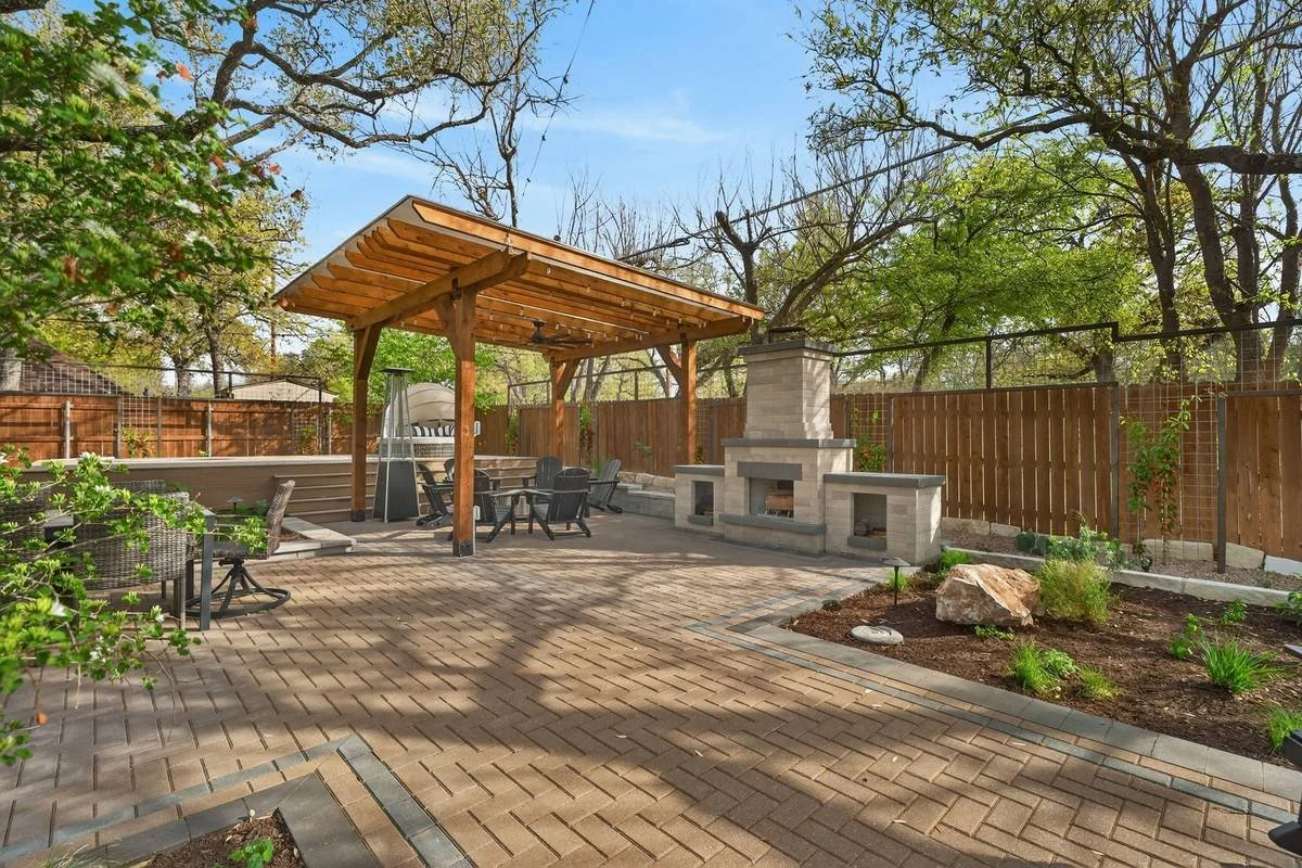 Second cedar pergola and stone fireplace beyond planting beds with limestone boulders — Southern Love Landscaping & Design