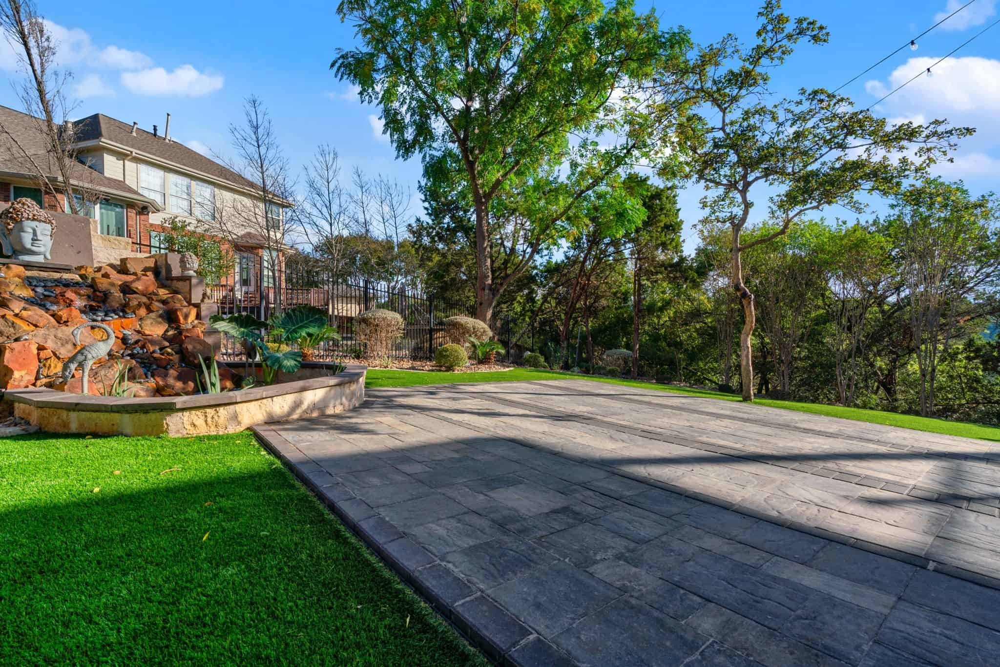 Spacious backyard paver patio with retaining wall seating and open layout ideal for gatherings and outdoor entertaining.