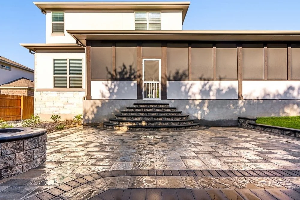Elegant paver patio entrance with stone steps and neutral paver design leading to a screened porch in a modern home.