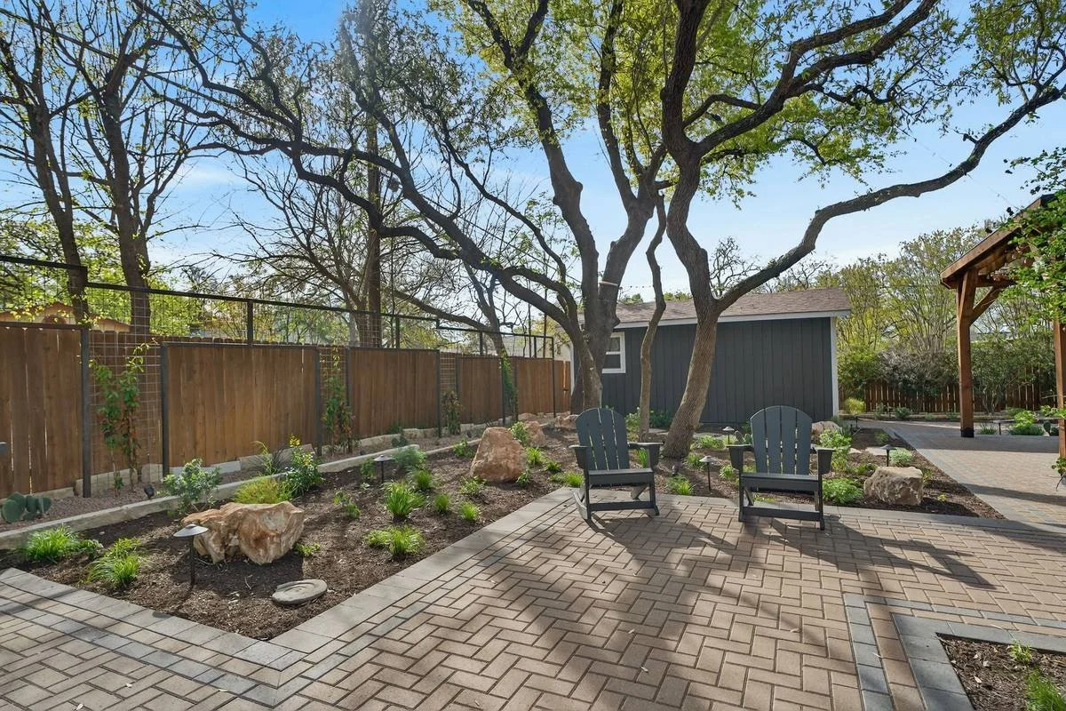 Adirondack chairs on a paver patio beside native and adapted planting beds — Southern Love Landscaping & Design