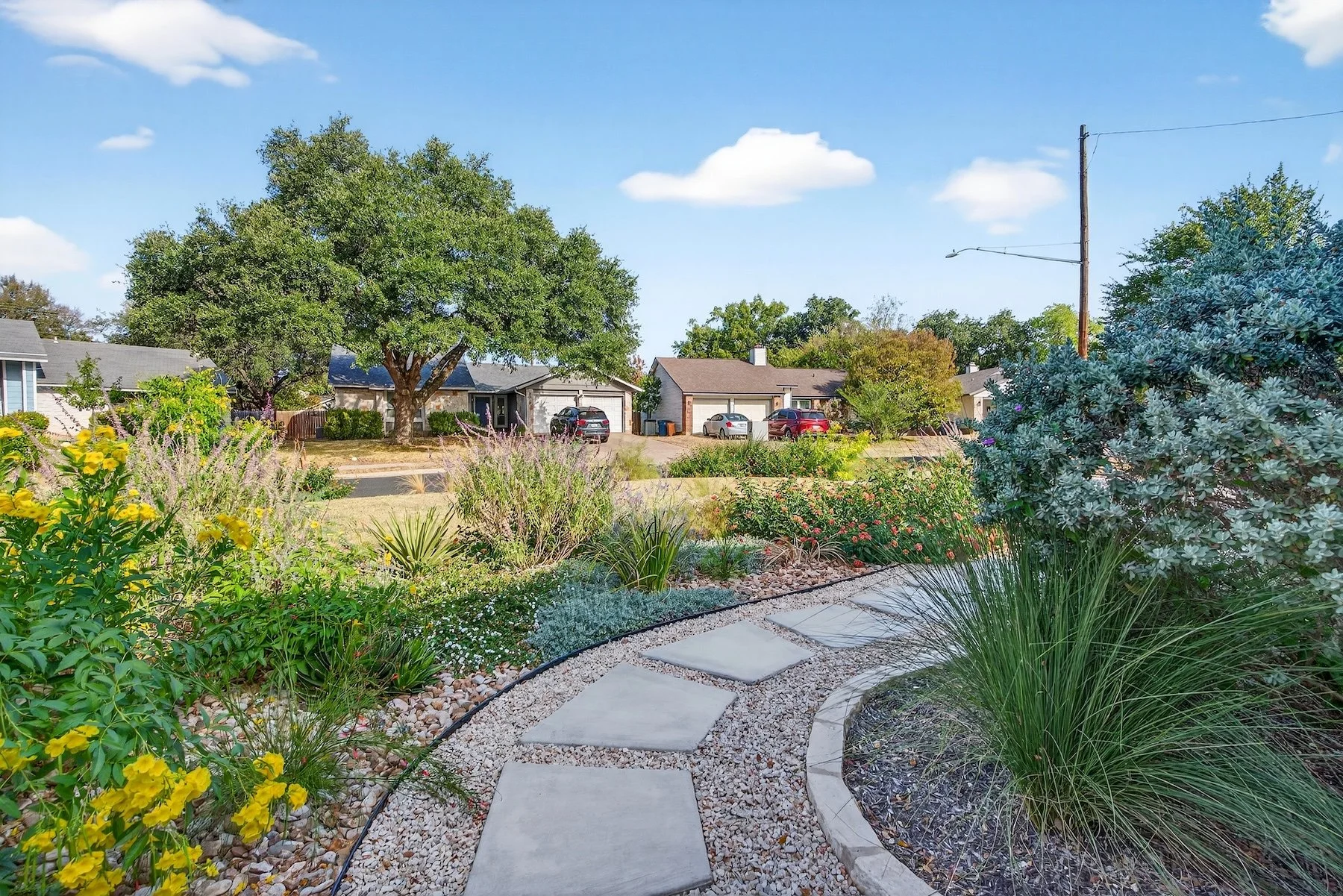 Flagstone path curving through a river rock bed with esperanza, muhly grass, and silver sage