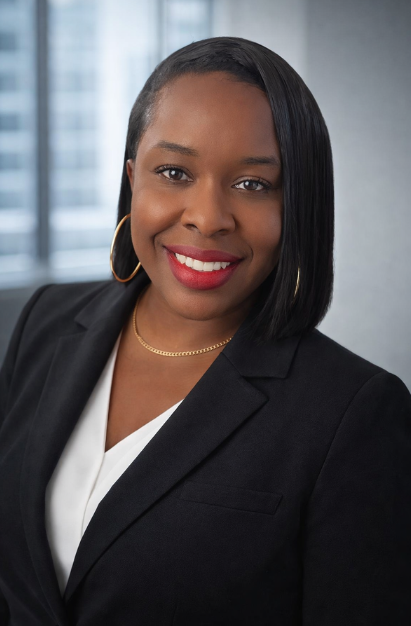 Professional woman with medium-length black hair, hoop earrings, red lipstick, and a black blazer smiling in an office setting.