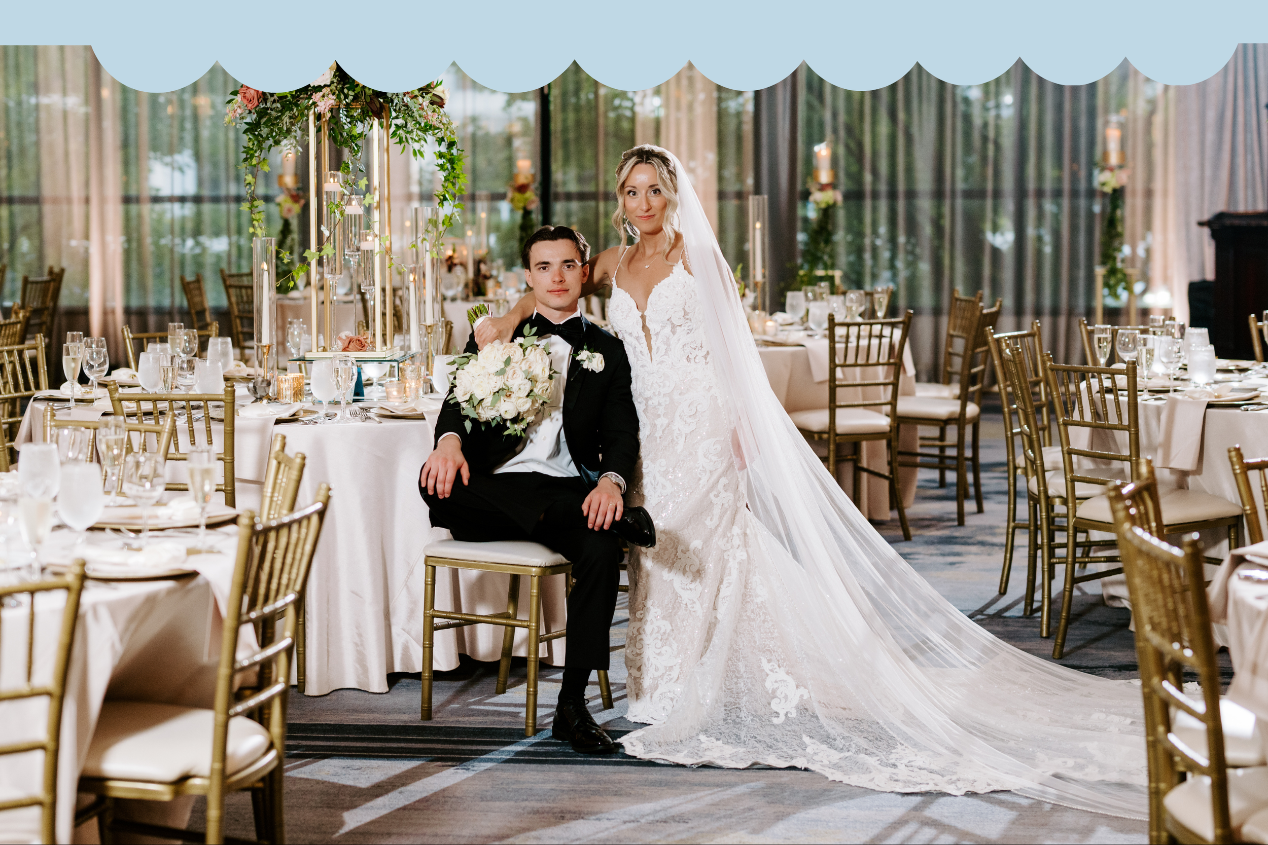 Bride and groom posing at their wedding reception, with elegant table settings and floral arrangements in the background.