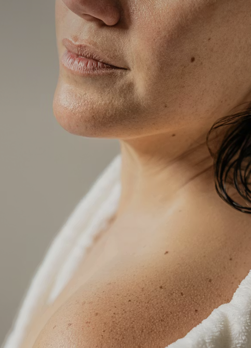 Close-up of a woman's lower face, neck, and shoulder showing smooth skin and a neutral expression.