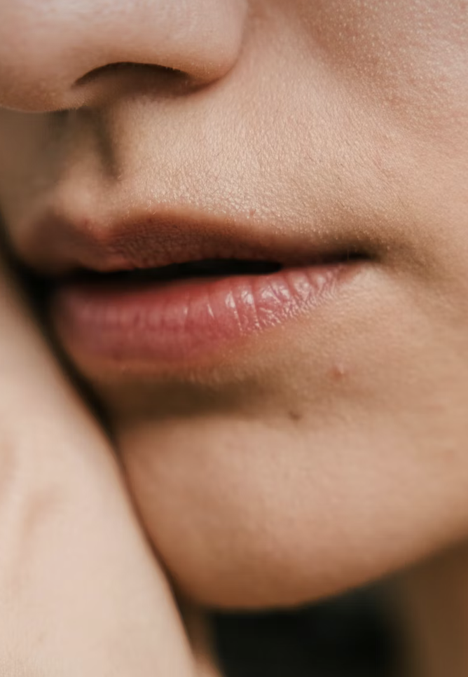 A close-up of a person's lips and part of their nose, showing smooth skin and some natural texture.