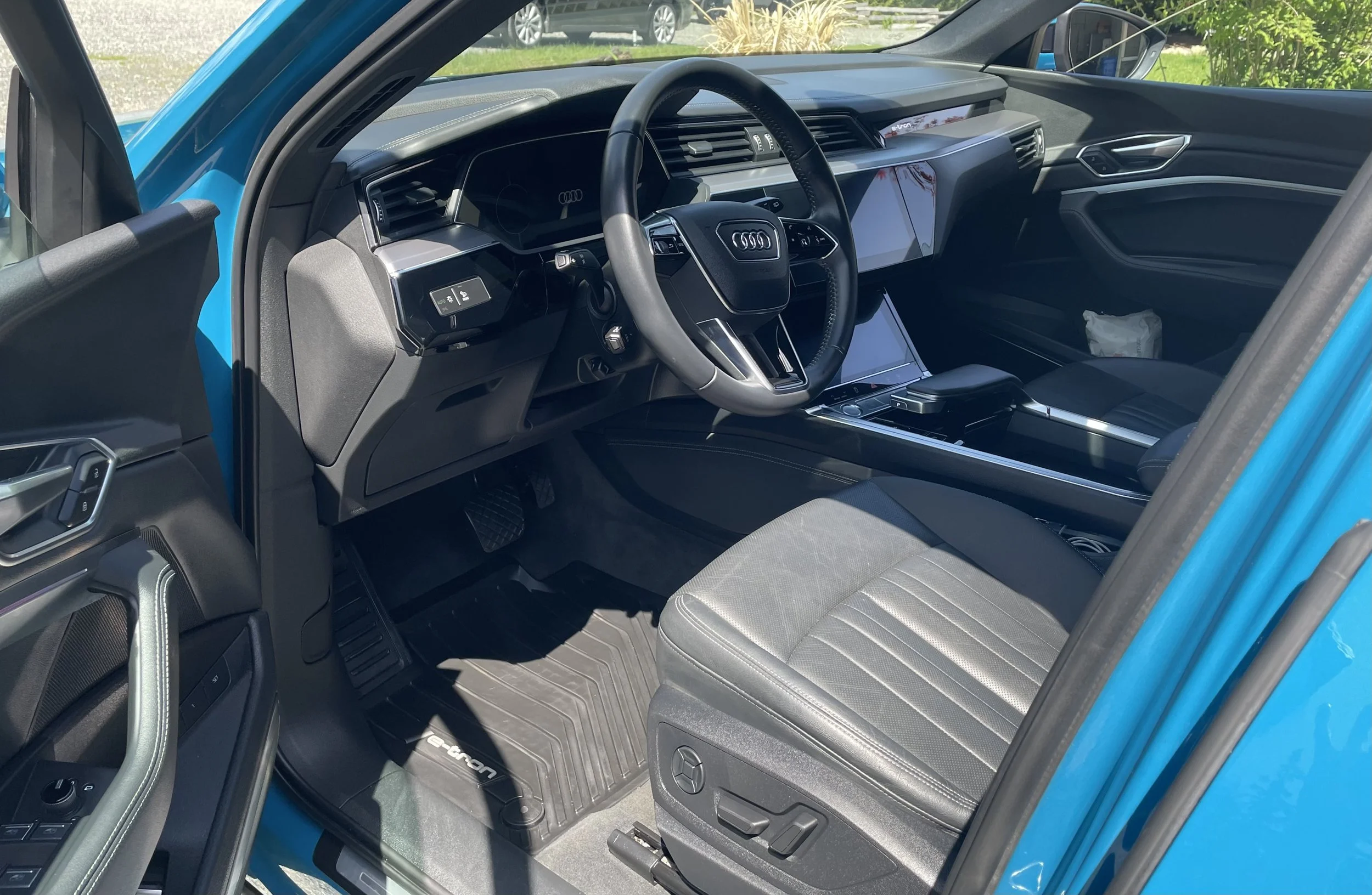 Interior of a blue Audi vehicle showing the dashboard, steering wheel, center console, and front passenger seat.