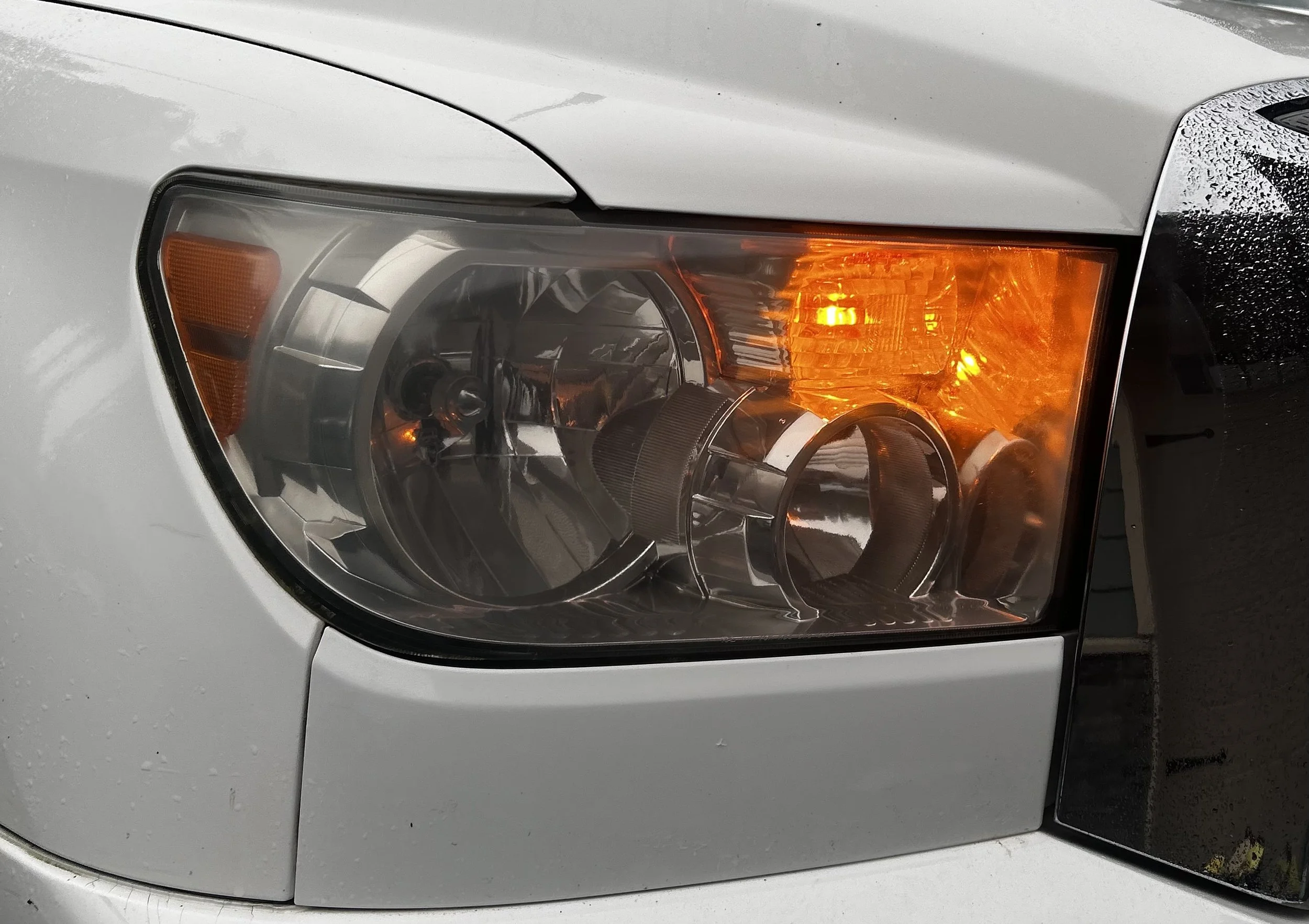 Close-up of a car's headlight with the turn signal illuminated