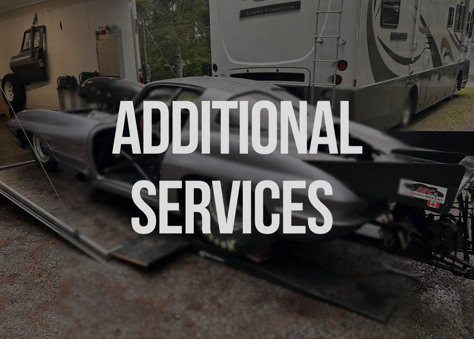 Race car on a trailer in a garage with RV in the background.