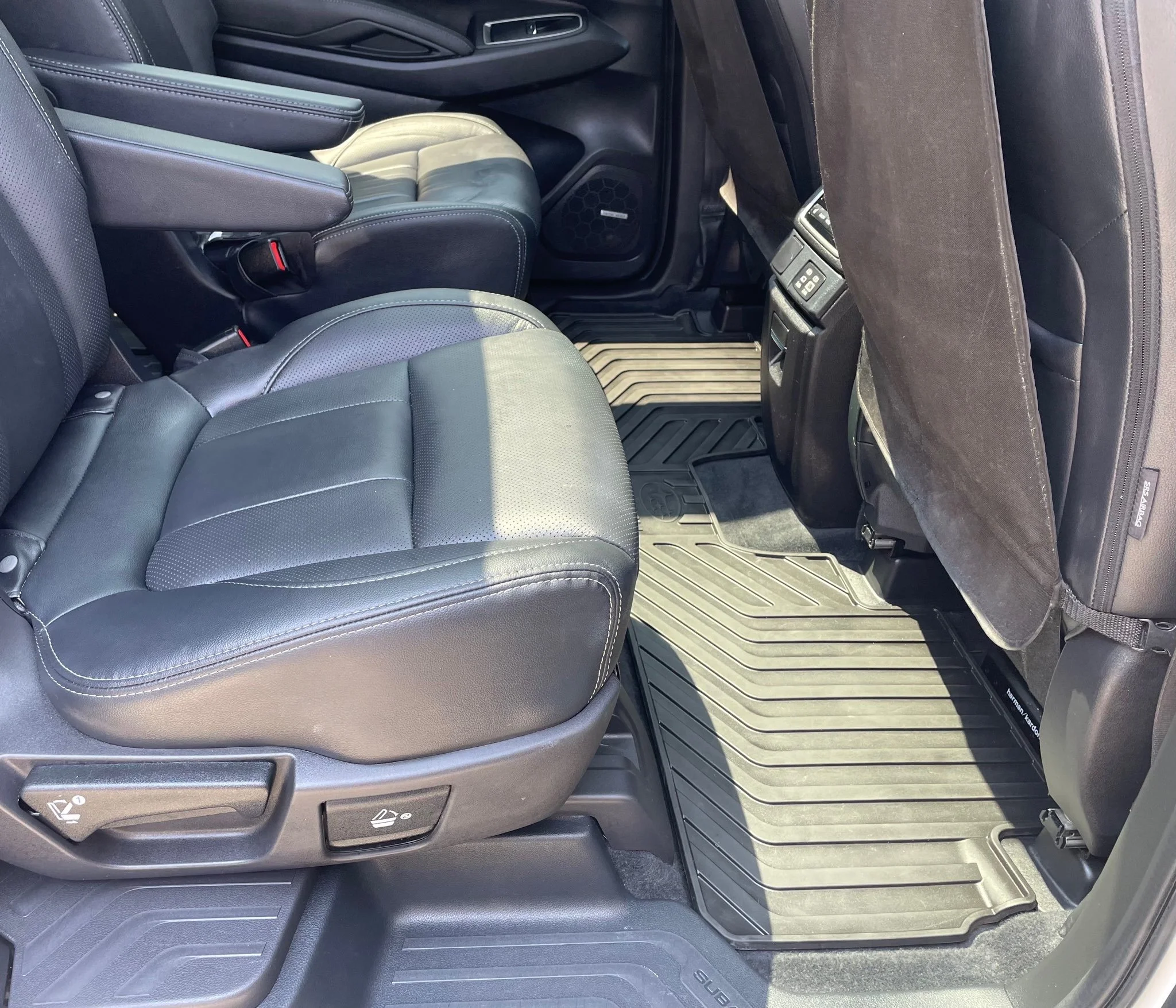 Interior of a vehicle showing two black leather seats with seat adjustments, and a floor mat with vehicle brand logo.