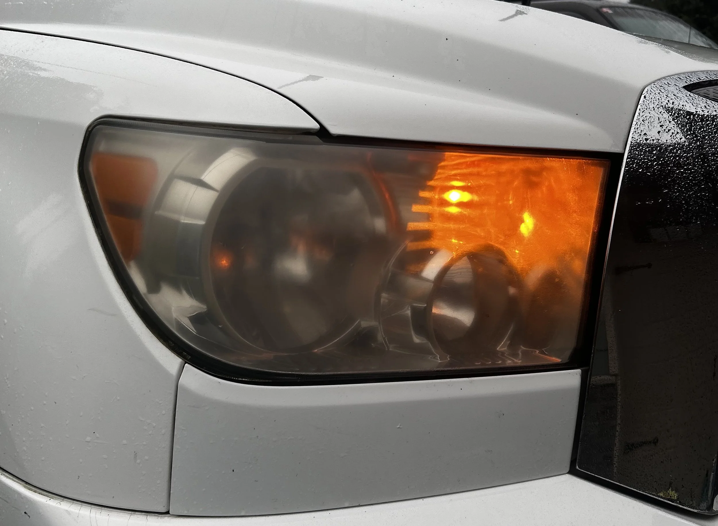 Close-up of a car's front headlight with the indicator light turned on, showing the orange glow.