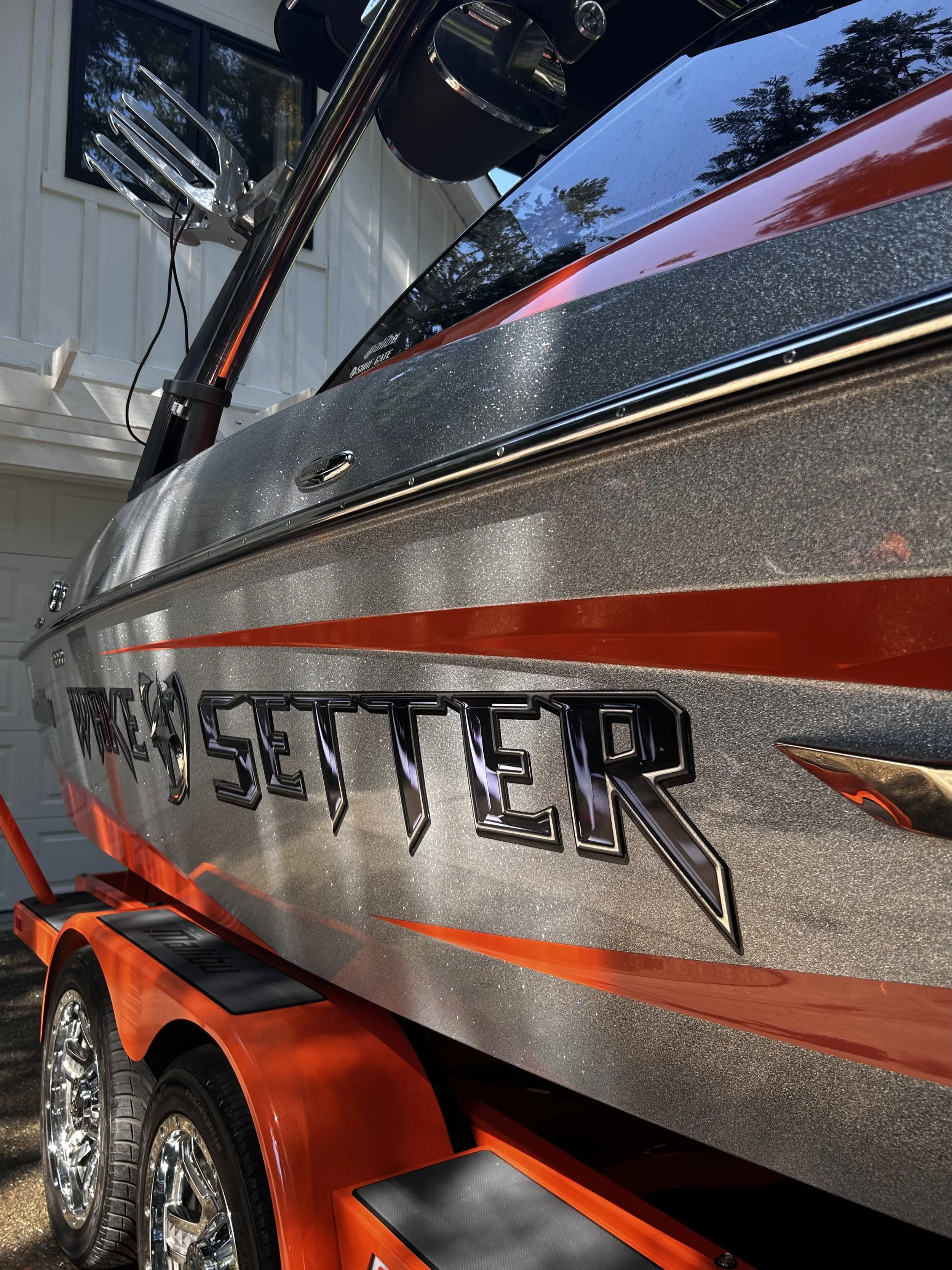 Close-up view of a boat with the word 'Setter' on its side, showing shiny metallic paint with orange and black accents, and chrome wheels.