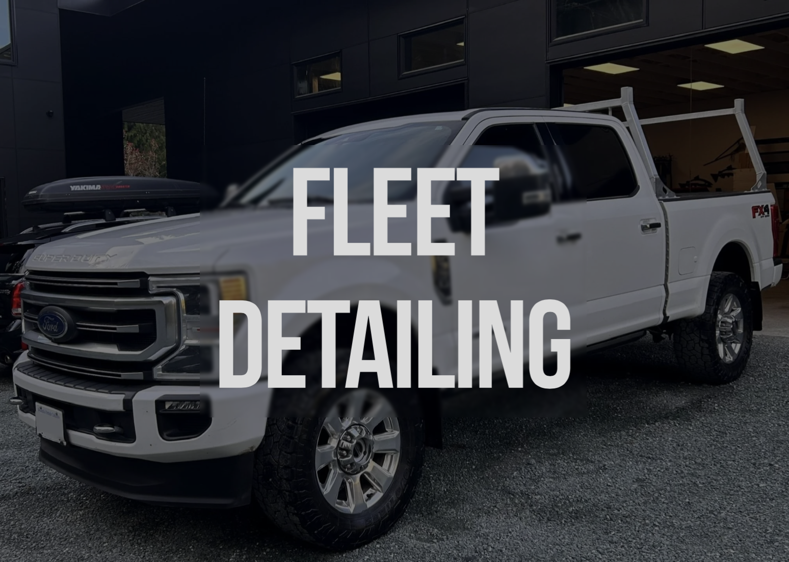 White pickup truck parked outside a modern black building.