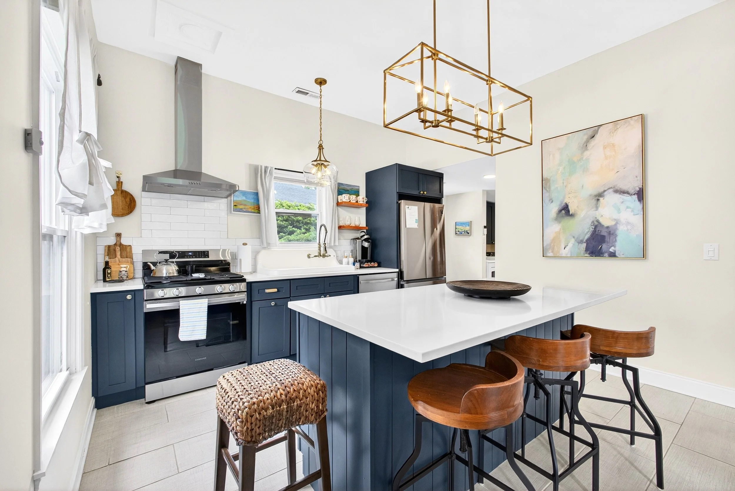 Kitchen with blue cabinets, white countertop, stainless steel appliances, and modern lighting fixtures.