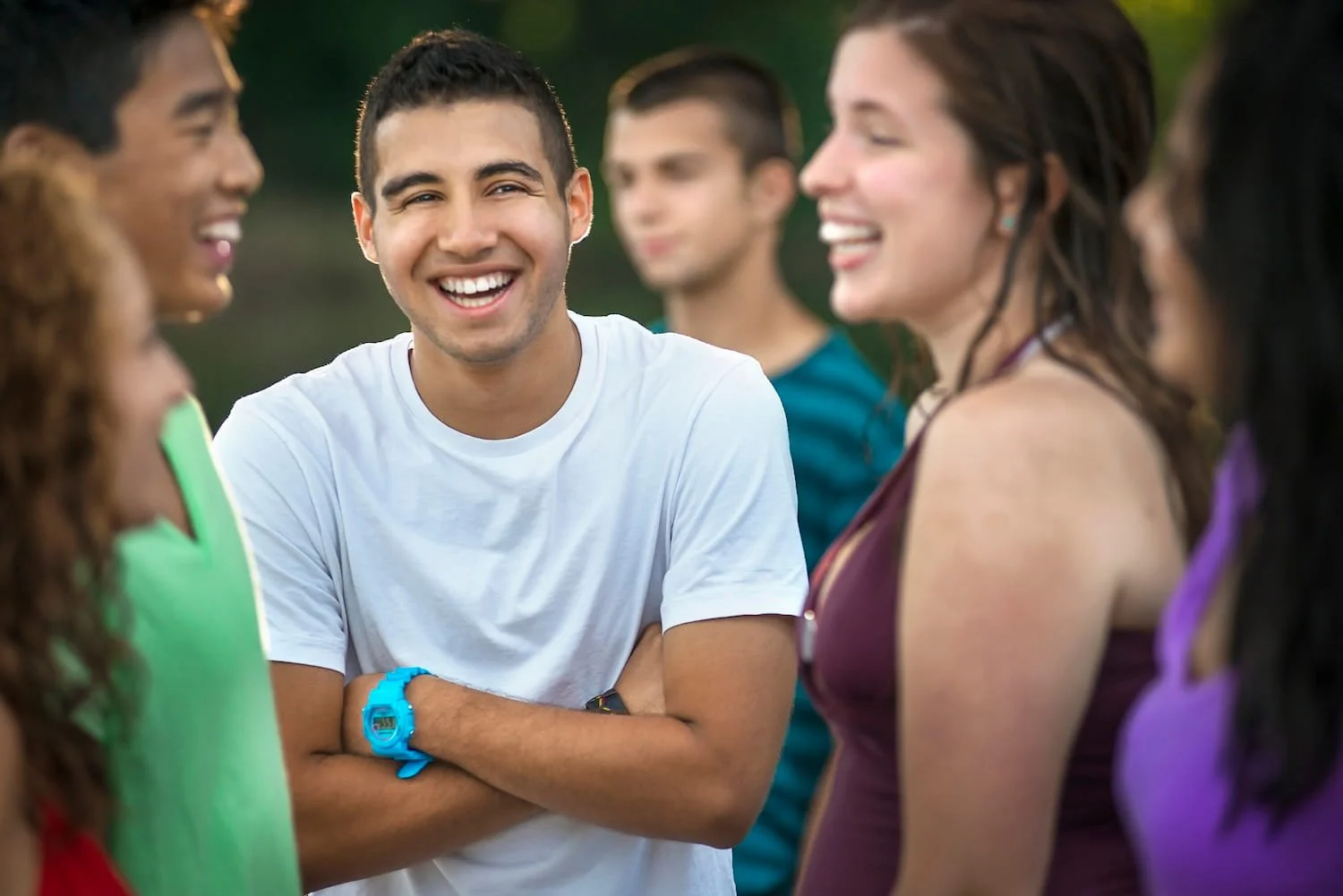Group of teenagers laughing together outdoors, representing peer support and community connection.