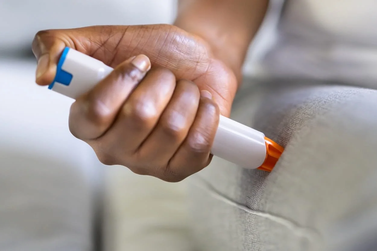 Person using a white and orange marker to mark the hem of a beige fabric garment.