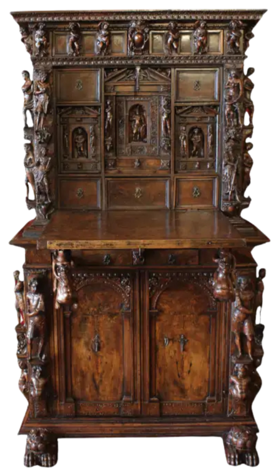 An antique wooden cabinet with ornate carvings, including small sculptures of figures and decorative patterns, made of dark polished wood.