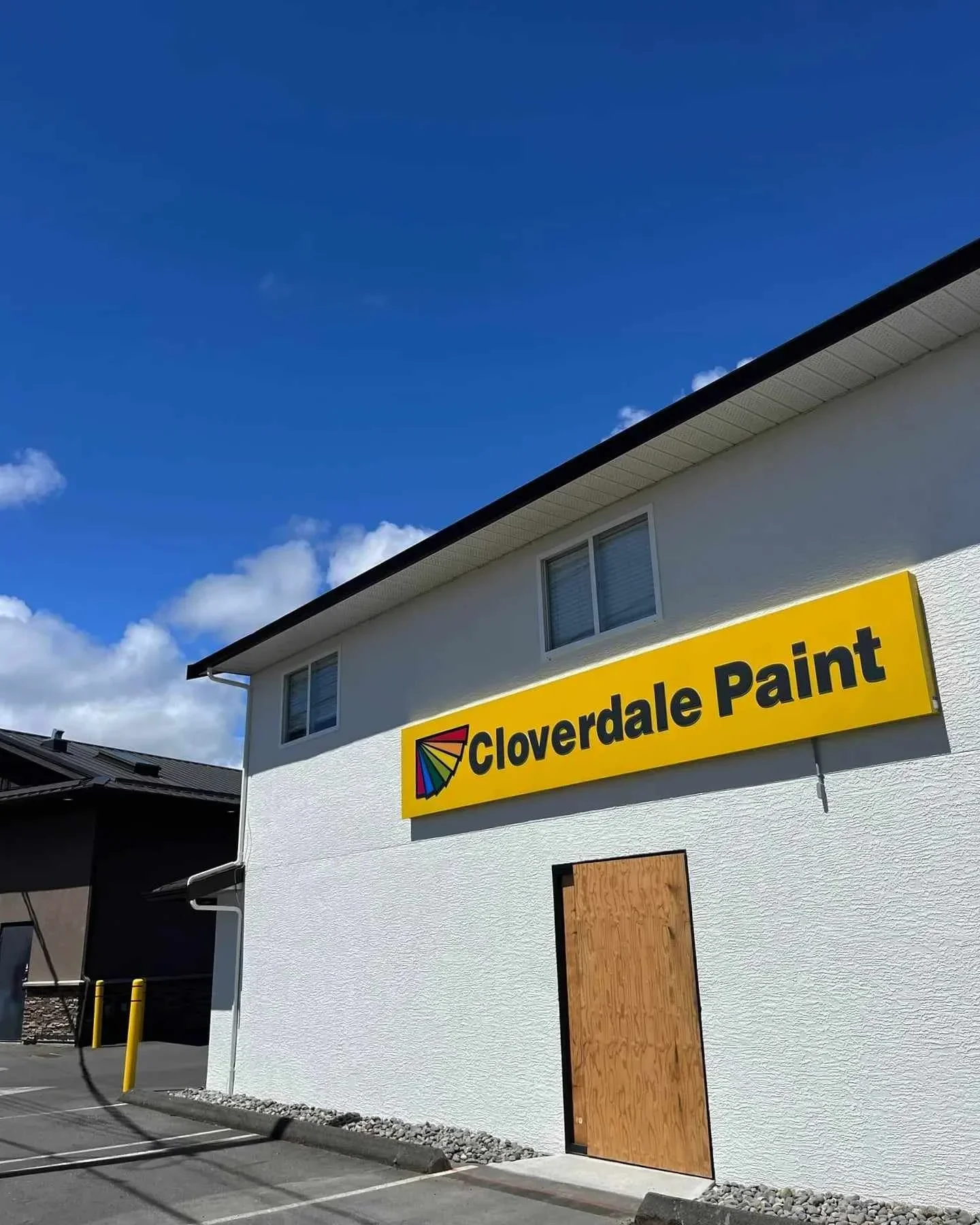 Building with a yellow sign reading 'Cloverdale Paint' and a colorful logo, set against a bright blue sky.