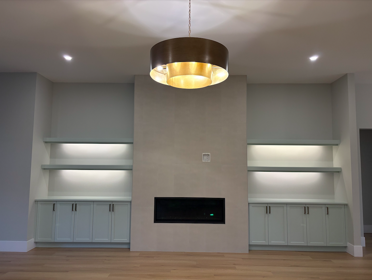 Modern living room with built-in white cabinets and shelves on either side of a central fireplace, minimalistic design, ceiling light, wood floor.