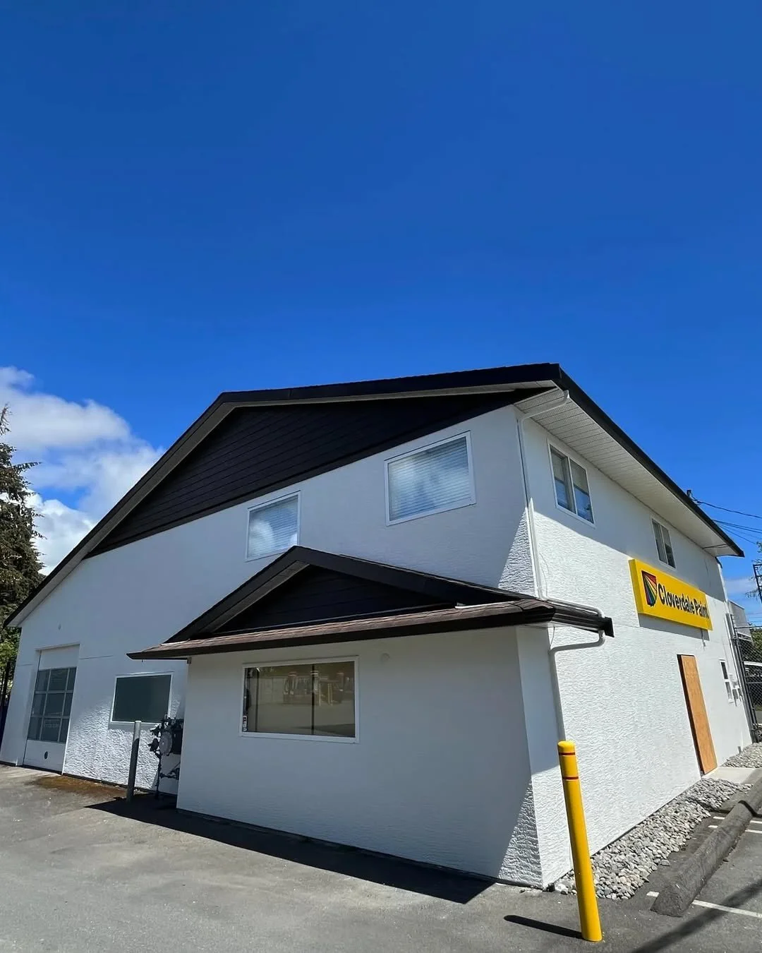 A two-story white commercial building with a yellow and black sign that reads 'Cloveara' under a bright blue sky.