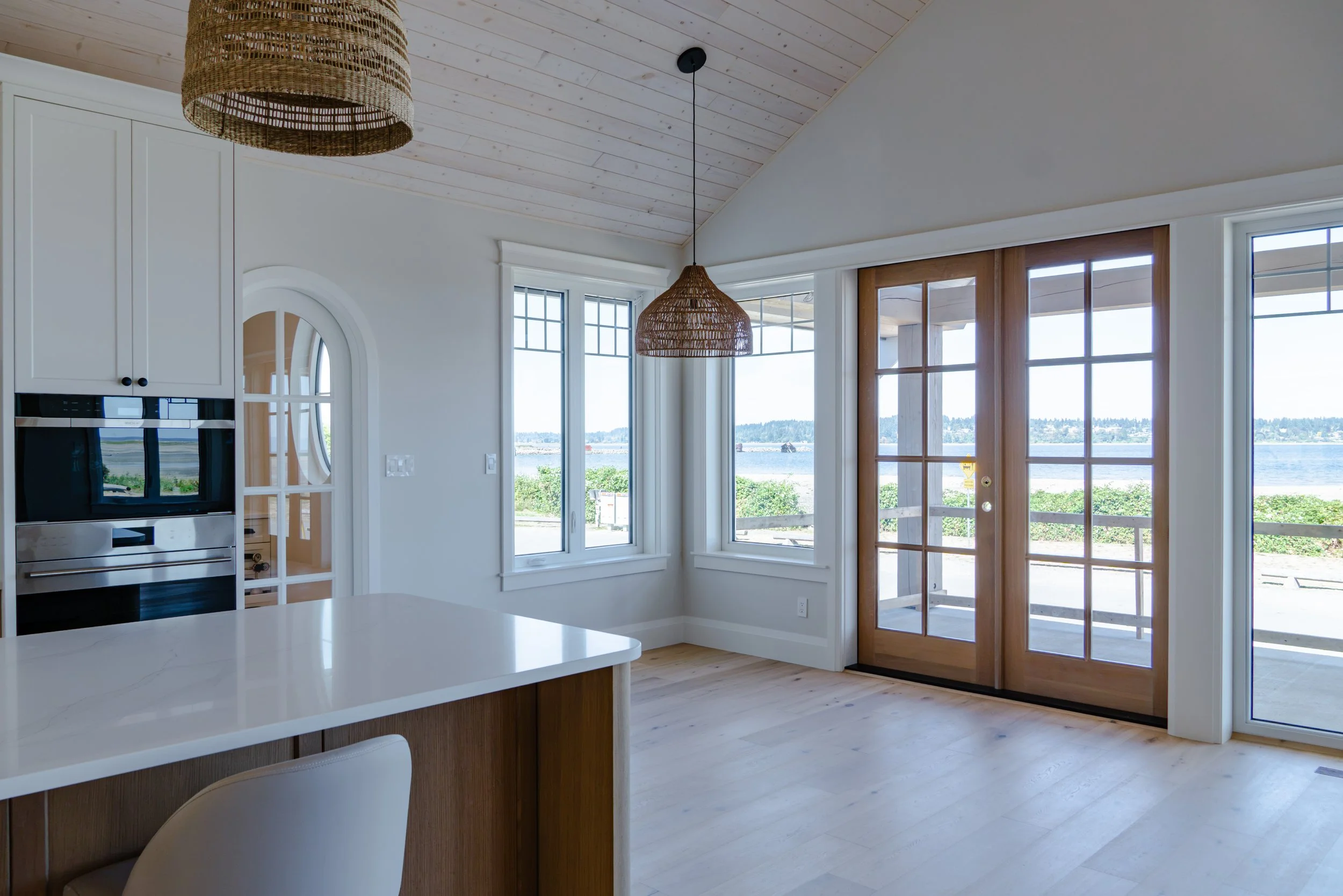 Living room with a modern electric fireplace set into a large, light-colored stone wall, flanked by two built-in cabinets with shelves and lighting, hardwood floors, and a window on the right side.