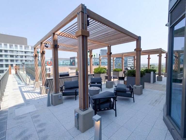 Rooftop terrace with wooden pergolas, black chairs, and planters in an urban setting.