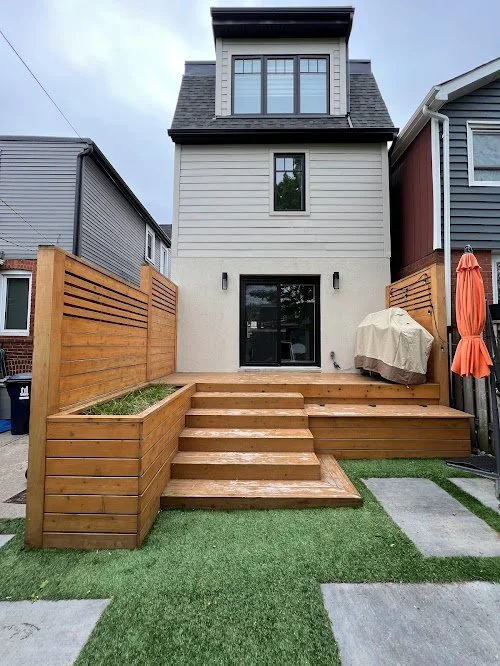 Pressure treated deck maintenance in Toronto preventing cracking with regular sealing. Backyard with wooden deck stairs, built-in garden beds, sliding glass door, and privacy fencing, adjacent to neighboring houses.
