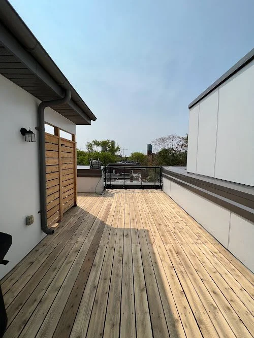 Pressure treated deck refinishing in the GTA featuring new board installation and staining. Outdoor rooftop balcony with wooden flooring.