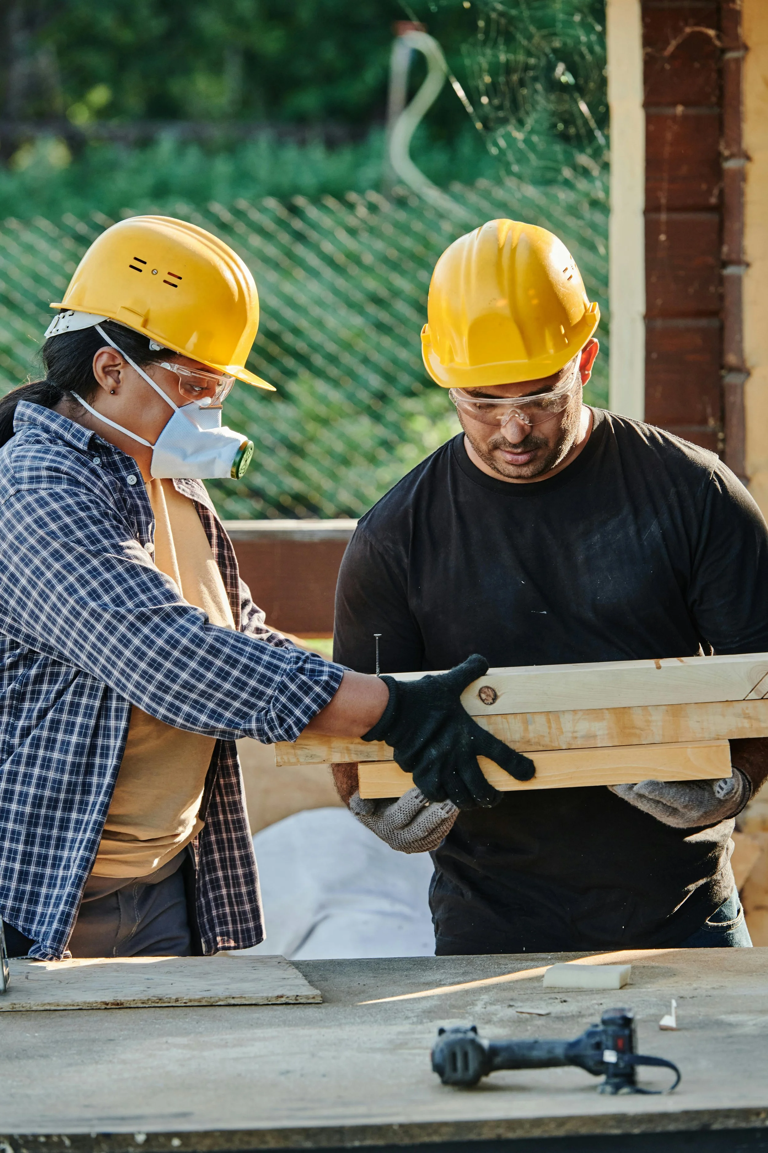 Construction workers handing off a pile of wood