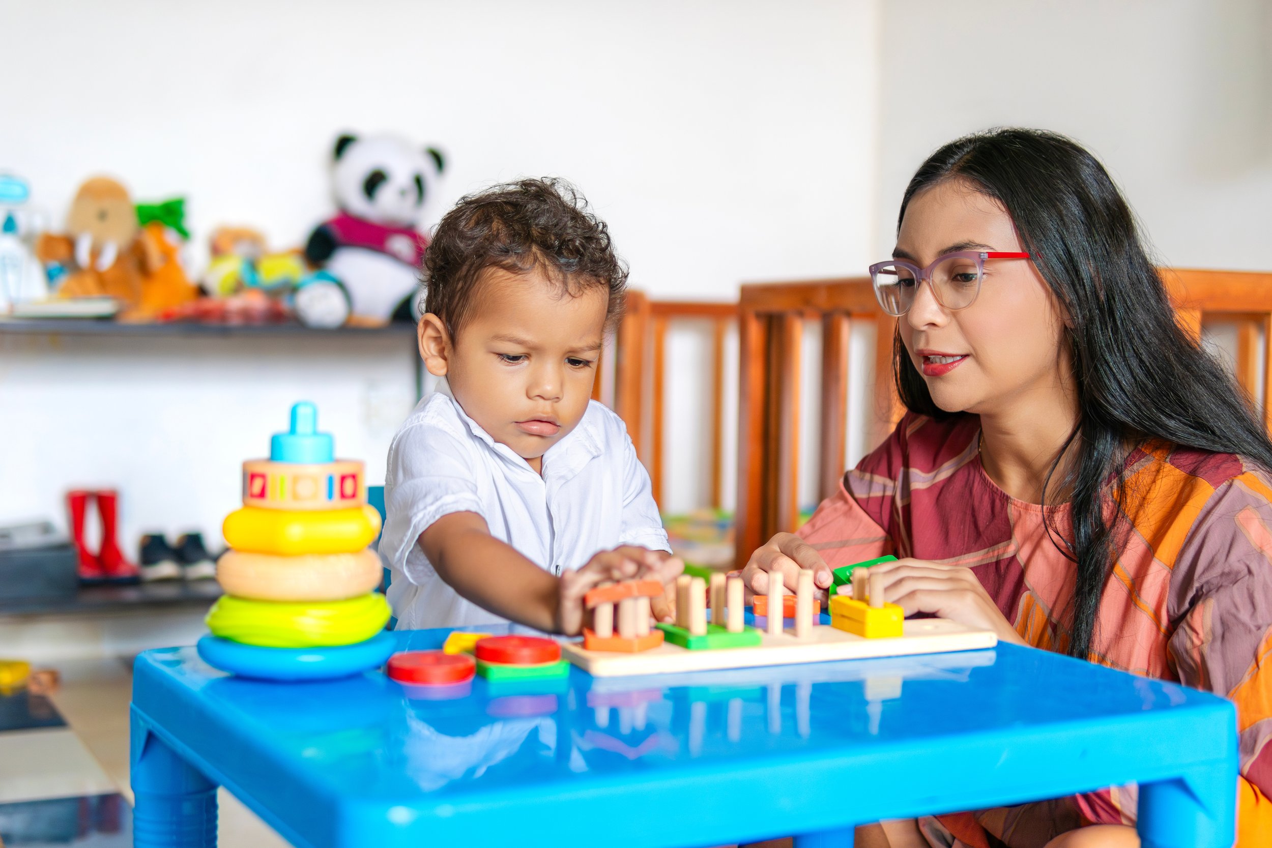 Child exploring a shape-sorting toy with guidance during structured sensory play